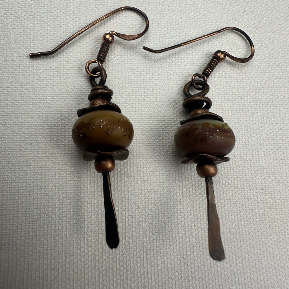 Bronze colored hardware and tan/brown and speckled bead. Dangle earrings.